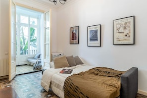 A bedroom with a bed, a chair, a table, and a door leading to a balcony. - Authentic, Private Garden / Paseo de Gracia (08008 Barcelona)