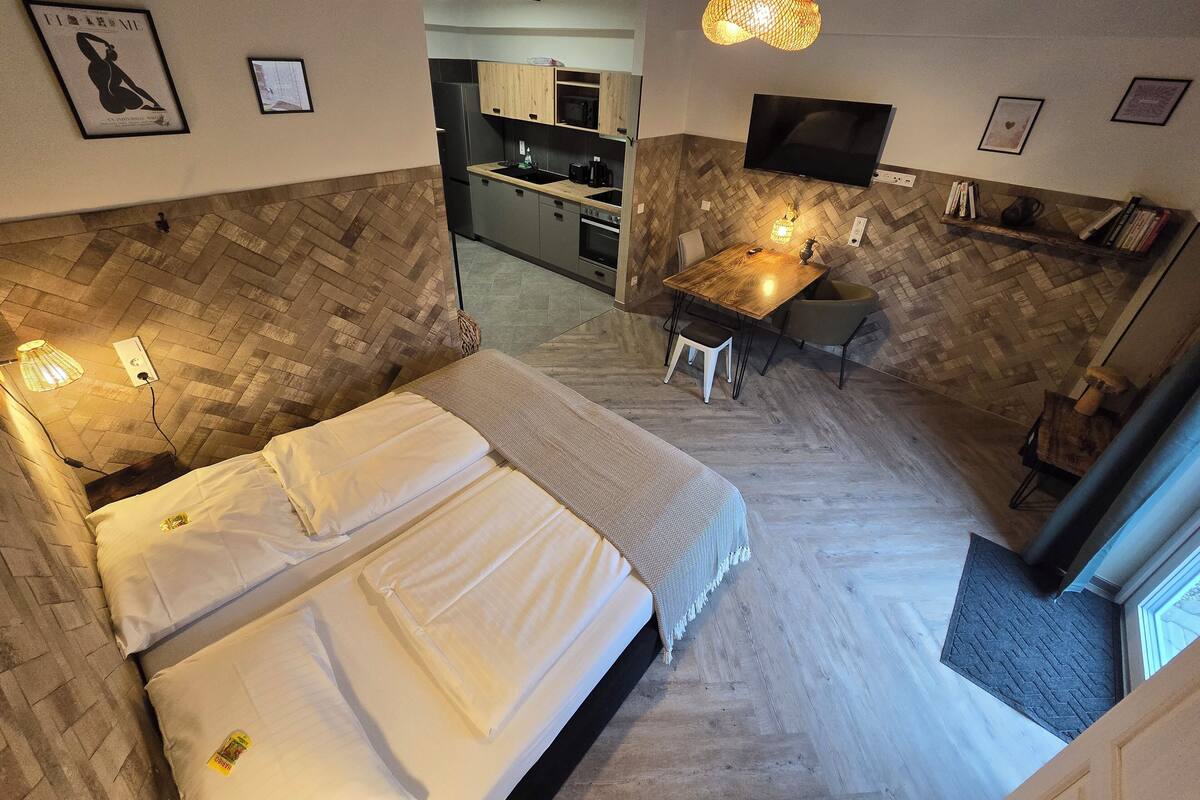 Een hotelkamer met een bed, een bureau, een stoel, een televisie en een keuken in de achtergrond.