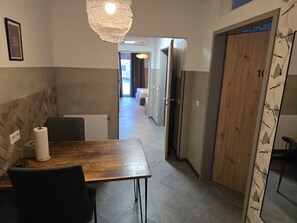 Un pasillo con una mesa y sillas de madera, una lámpara colgante y una puerta con panel de madera.