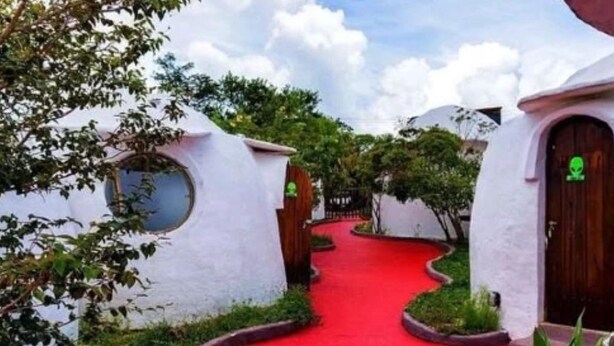 A pathway leading through a series of white-walled buildings with wooden doors and a red carpet. - Pousada Abduzidos (Alto Paraíso de Goiás)