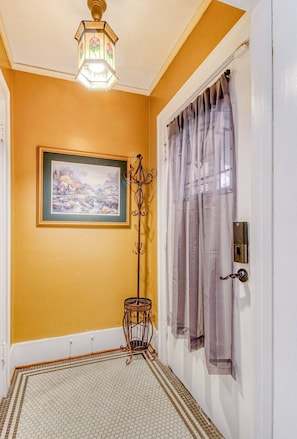 A hallway with a door, a framed painting, a floor lamp, and a patterned floor.