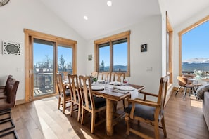A dining area with wooden chairs and a table set for four, large windows with a view of snow-capped mountains, and a wooden ceiling. - Alma Mountain Escape - Views , Deck , Theater (Fairplay)