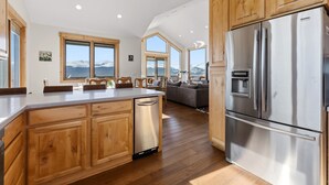 A modern kitchen with wooden cabinets, a stainless steel refrigerator, and a large island with a dishwasher. - Alma Mountain Escape - Views , Deck , Theater (Fairplay)