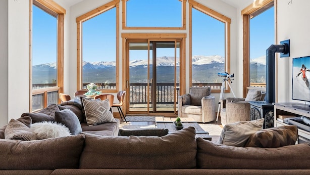 A spacious living room with a large window, a balcony, and a television. - Alma Mountain Escape - Views , Deck , Theater (Fairplay)