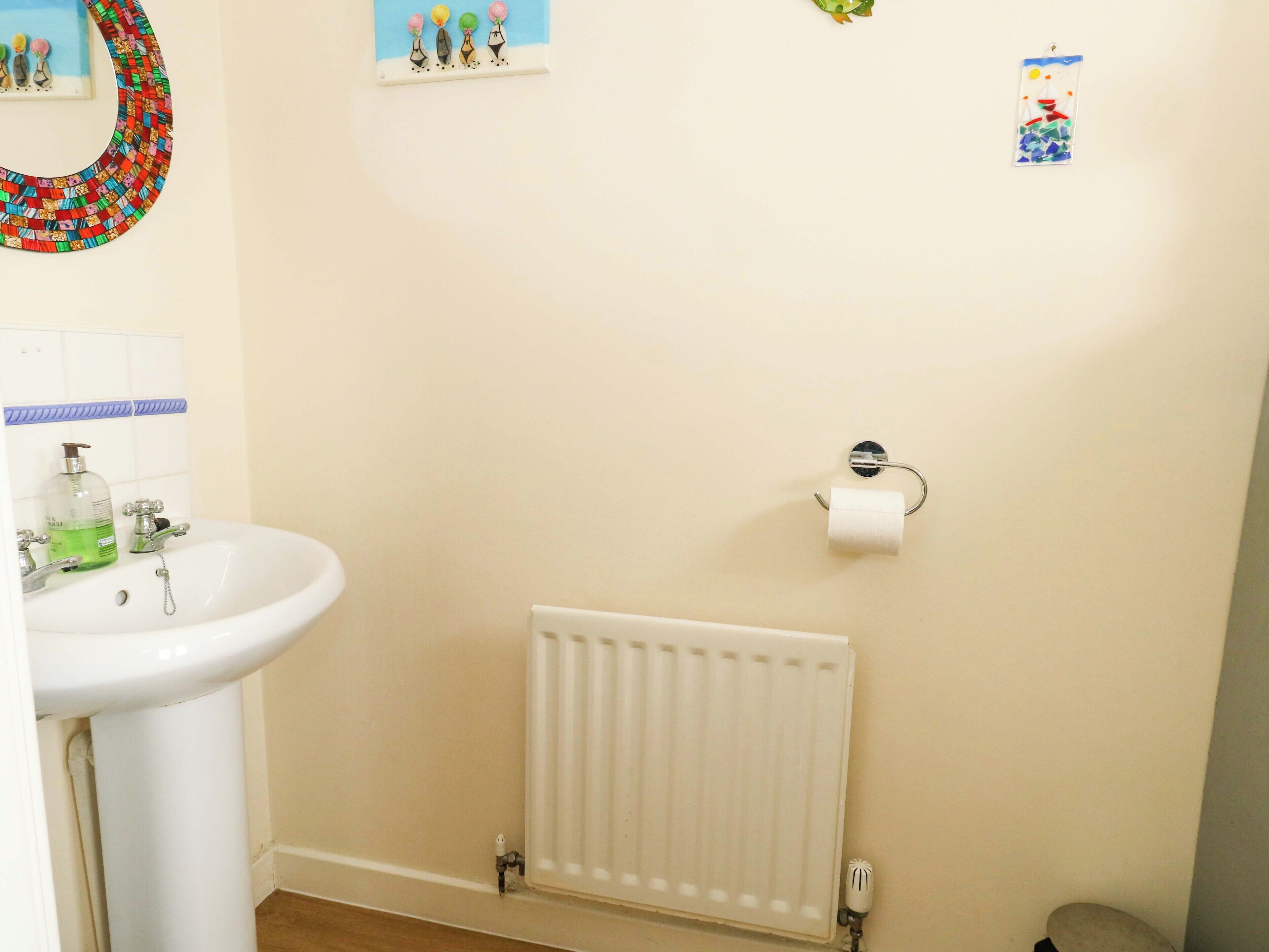 A bathroom with a white sink, a toilet, and a radiator.