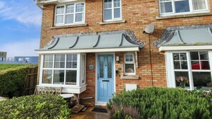 A two-story brick house with a blue front door, white windows, and a satellite dish. - Still Waters (Weymouth)