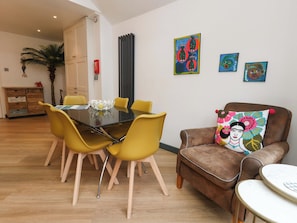 A dining area with a black table, yellow chairs, and a brown armchair with a colorful pillow.