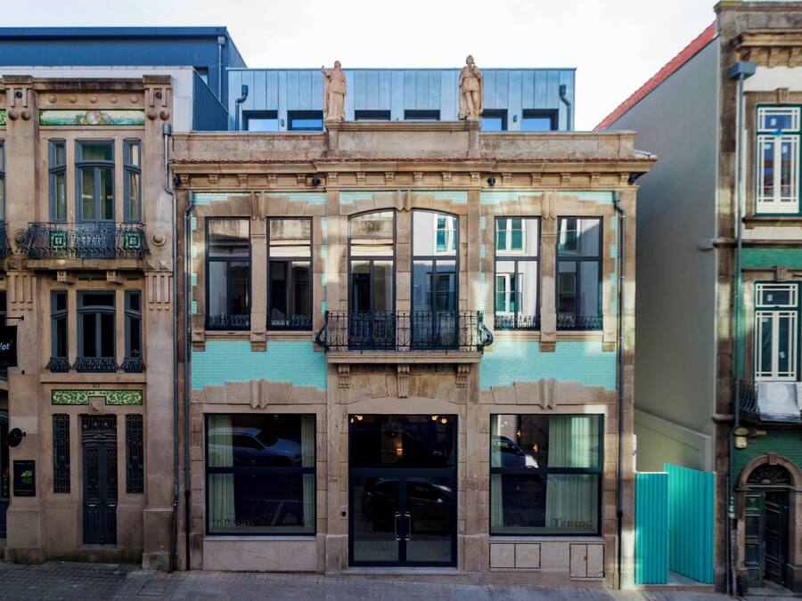 Un edificio con entrada central, ventanas amplias y un balcón con barandilla.