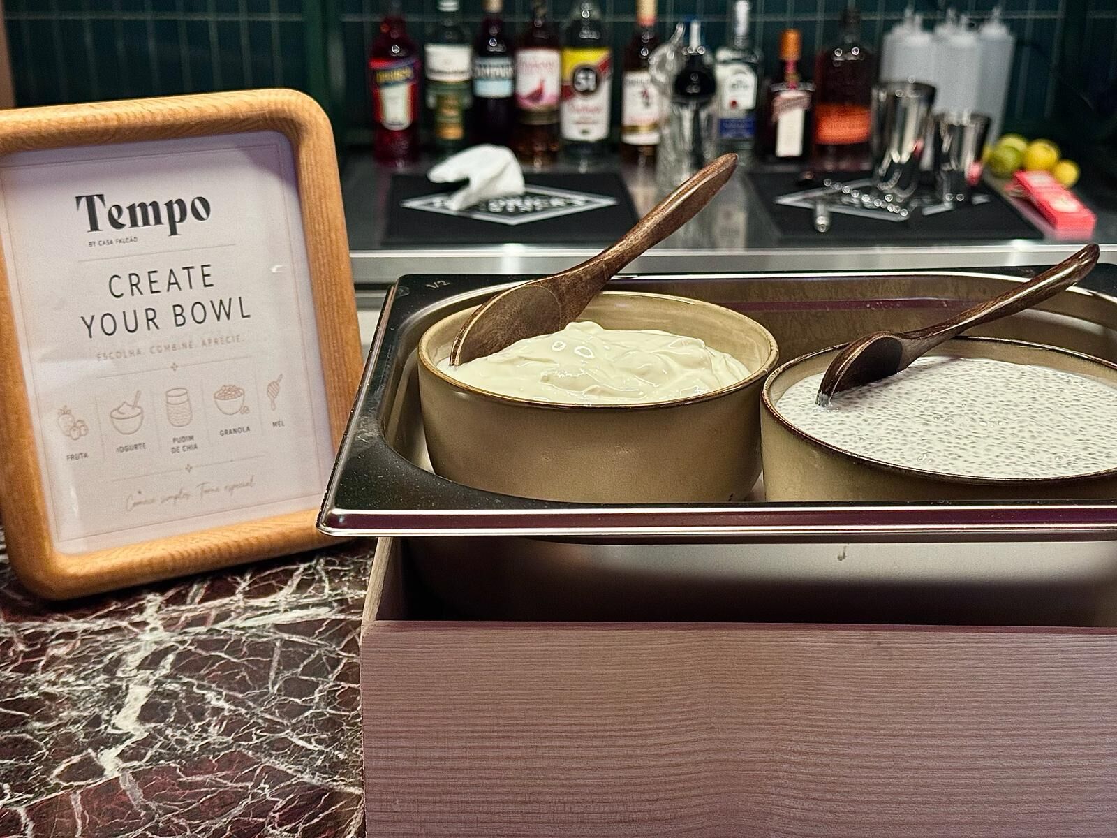 A kitchen counter with a sign reading 'Tempo CREATE YOUR BOWL' and two bowls with spoons.