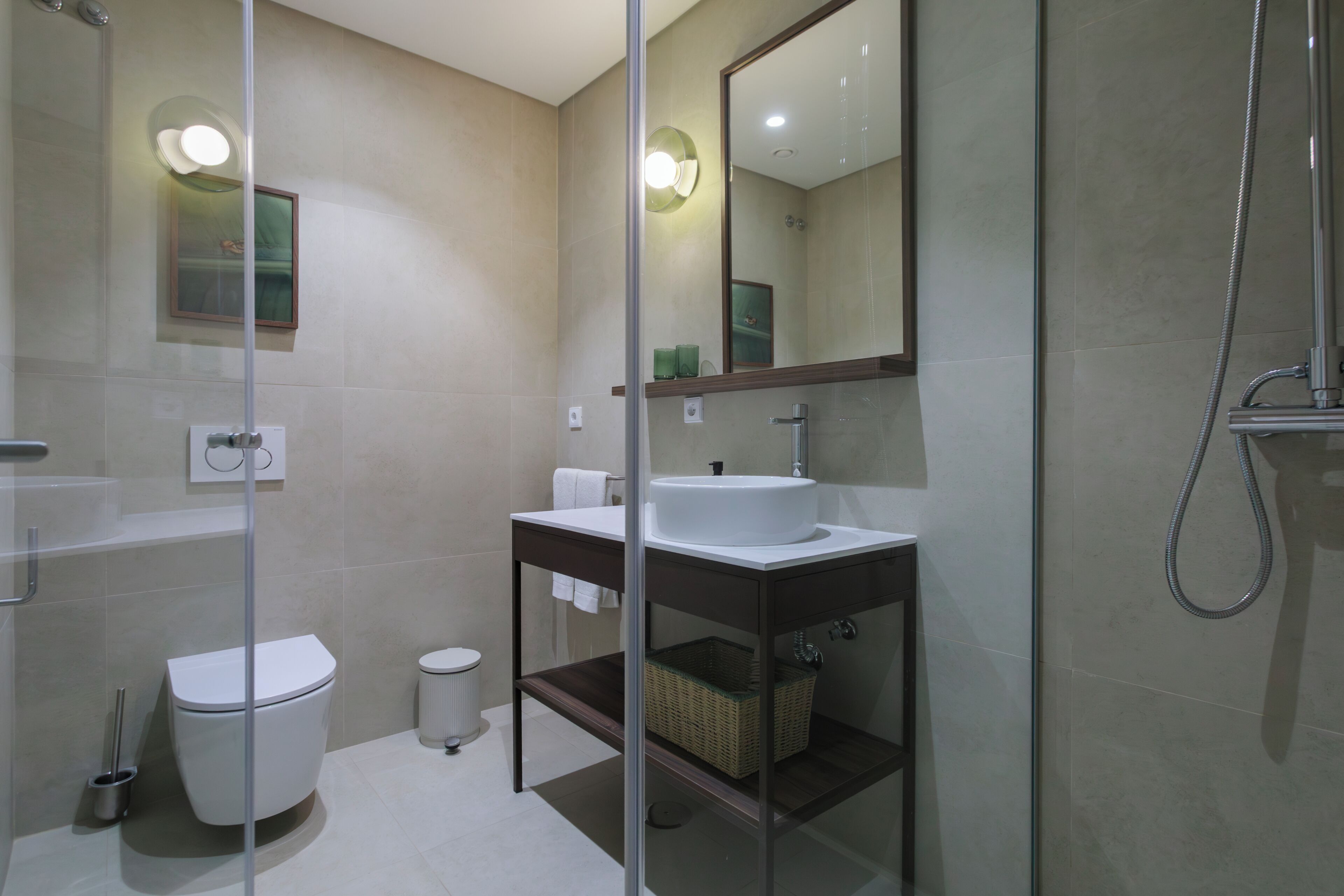 A modern bathroom with a glass shower enclosure, a white sink, and a toilet.