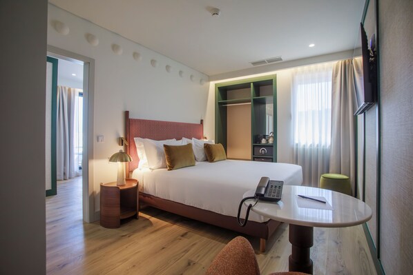 A hotel room with a bed, bedside table, lamp, phone, and a small table with a chair. - Casa Falcão Boutique Hotel by Aspasios (Porto)