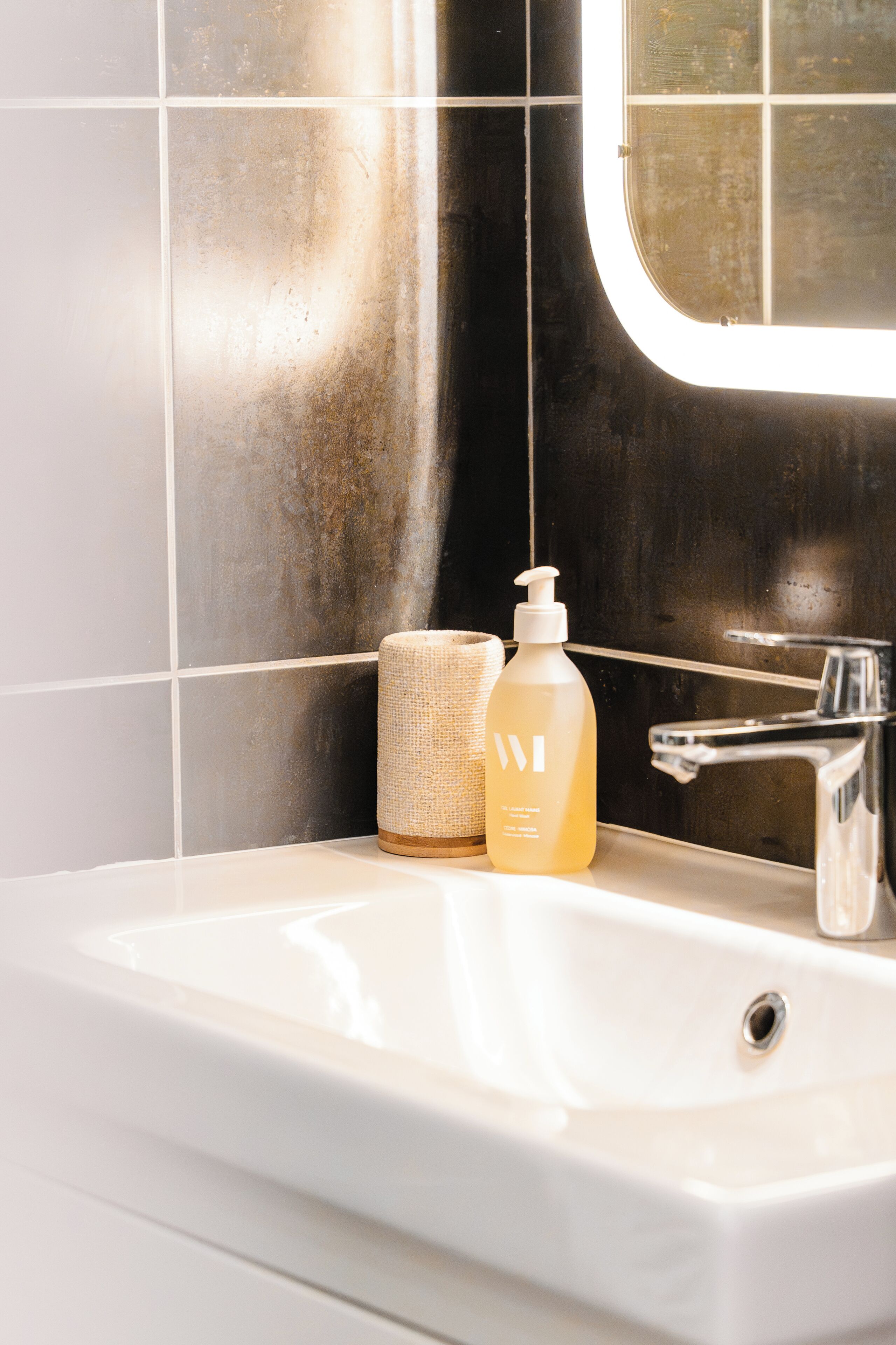 A bathroom with a white sink, a bottle of lotion, and a towel.
