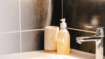 A bathroom with a white sink, a bottle of lotion, and a towel.