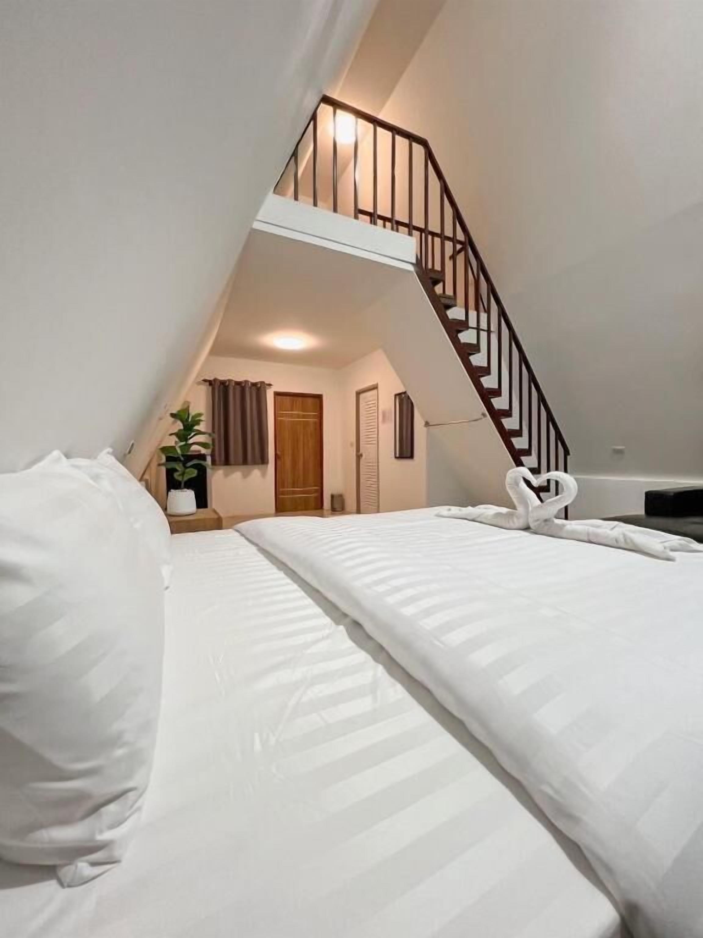 Ein Schlafzimmer mit einem Bett, einer Holztreppe und einem kleinen Topfpflanzen.