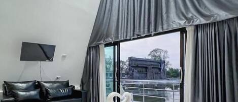 Una habitación de hotel moderna con una cama grande, un televisor de pantalla plana, un sofá de cuero y vistas a un edificio a través de la ventana.