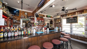 A bar with a wooden counter, multiple stools, and a variety of bottles. - AFTER HOURS ~ On Duval St, Adult Only, Adjoining Rum Bar & Nearby Beaches! (Key West)