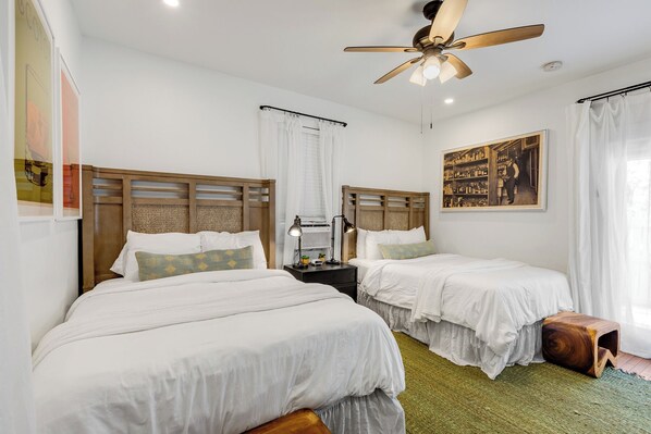 A hotel room with two beds, a ceiling fan, a nightstand with a lamp, and a painting on the wall. - SMUGGLER'S COVE ~ On Duval St, Adult Only, Adjoining Rum Bar & Near Beaches! (Key West)