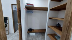Armadio a muro con ripiani in legno, una barra appendiabiti e un piccolo sgabello.