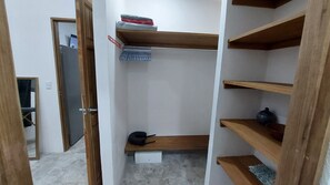 A walk-in closet with wooden shelves, a hanging rack, and a small step stool.