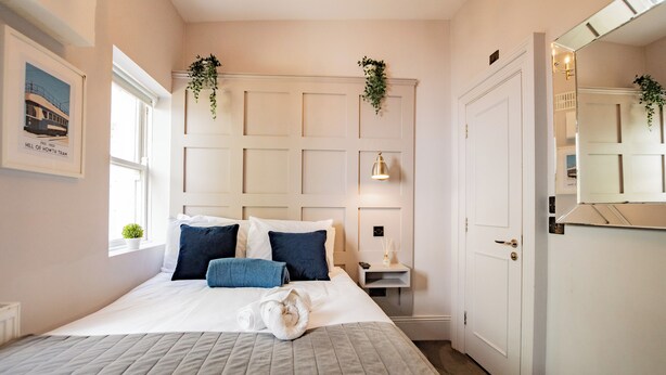 A neatly arranged bedroom with a large bed, bedside tables, a mirror, and a window. - Seaside Getaway in Howth (Howth)