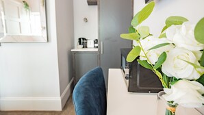 A modern room with a blue chair, a white desk, and a bouquet of white flowers. - Seaside Getaway in Howth (Howth)
