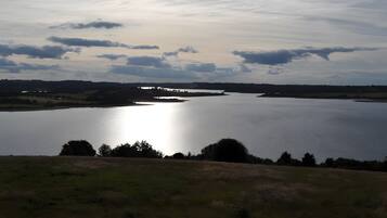 Une vaste étendue d’eau dont la rive est éloignée, entourée de champs ouverts et d’une végétation clairsemée.