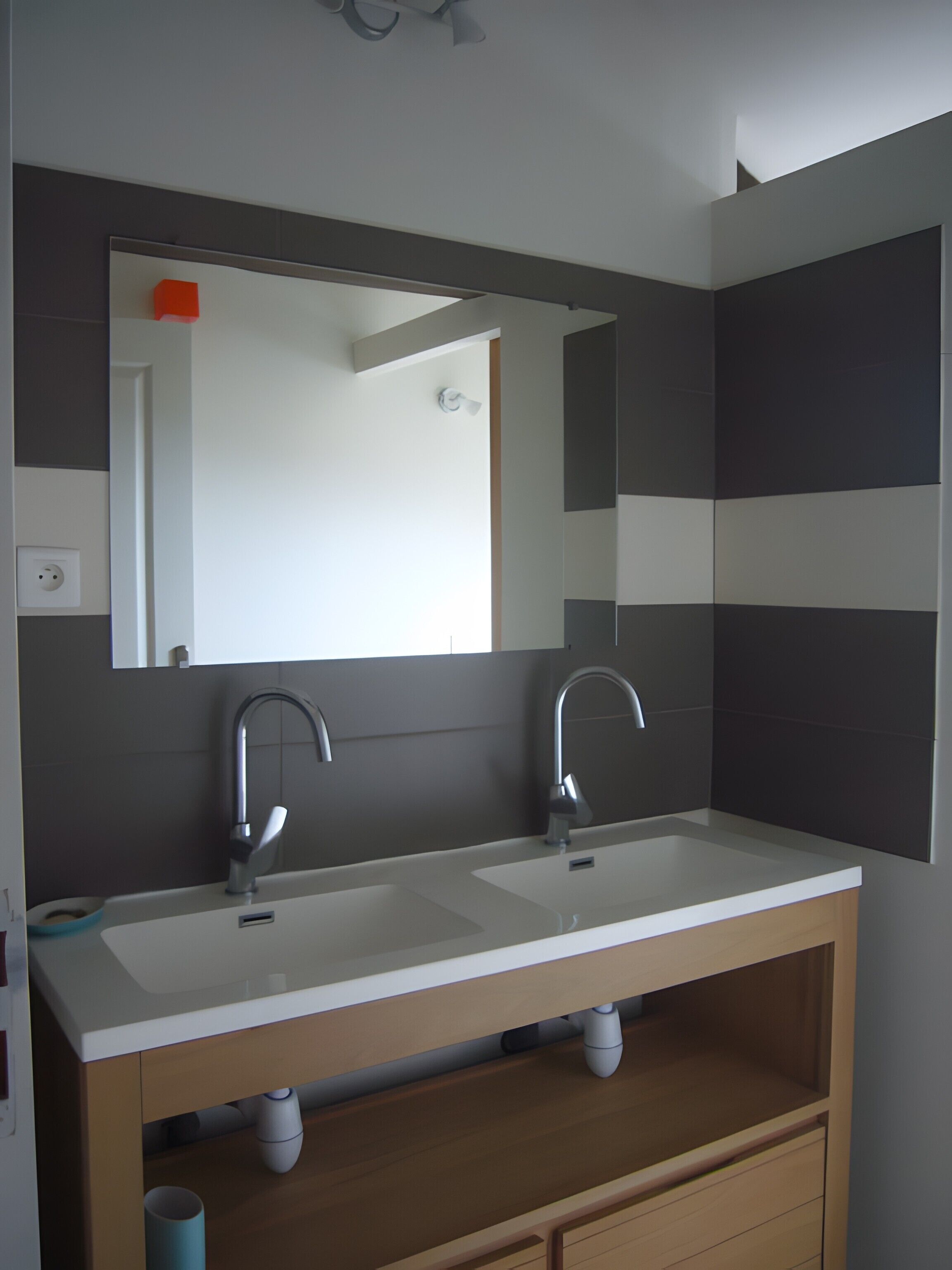 Ein modernes Badezimmer mit einem Waschbecken-Doppelplatz, einem Spiegel und einem Deckenventilator.