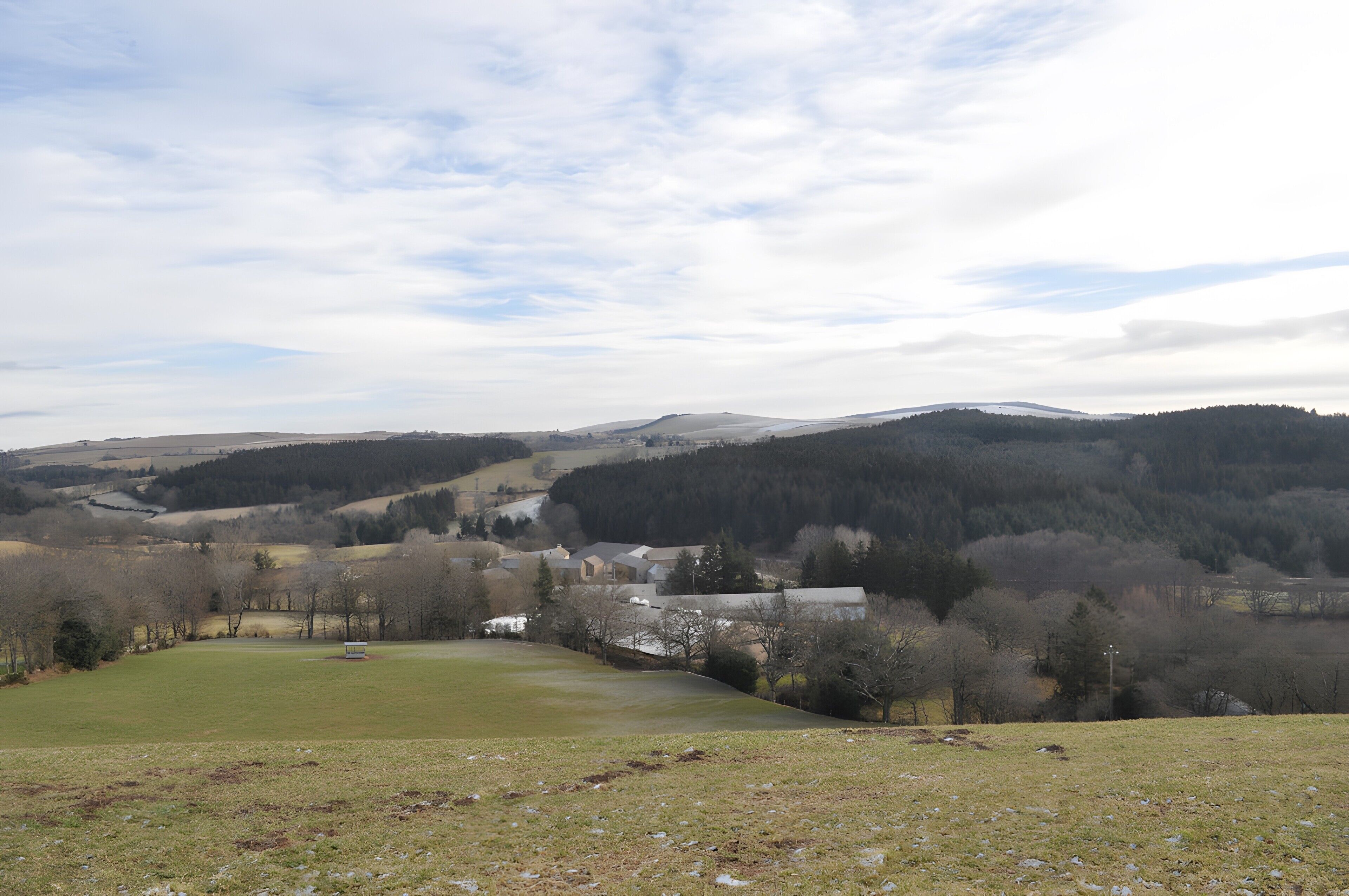 A rural landscape with rolling hills, a small village, and a clear sky.