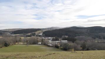 A rural landscape with rolling hills, a small village, and a clear sky.