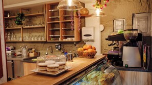 A bakery counter with pastries, a coffee machine, and shelves with glassware. - Hotel MachuPicchu Humantay (Aguas Calientes)