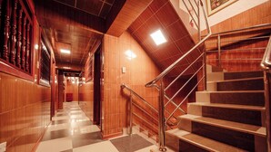 A hotel corridor with a checkered floor, wooden walls, and a staircase with metal railings. - Hotel MachuPicchu Humantay (Aguas Calientes)
