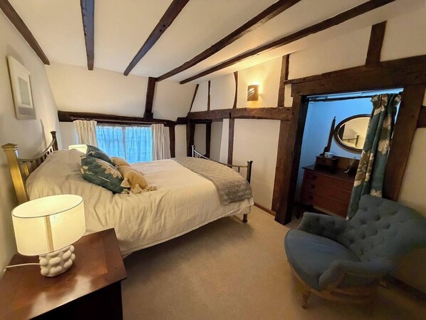 A bedroom with a bed, a bedside lamp, a chair, and a mirror.