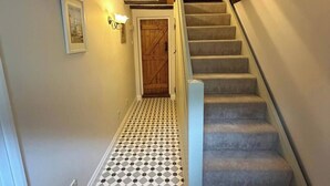 A staircase with a patterned floor leading to a wooden door.