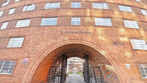Un edificio de ladrillo con una entrada en arco que dice 'St. Andrews Gardens'.