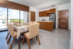 A modern kitchen with wooden cabinets, a stainless steel refrigerator, and a dining area with a table and chairs. - Sotogrande 3 rec con alberca cerca de Huayacan (Alfredo V. Bonfil)