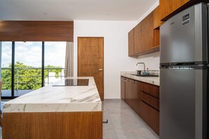 A modern kitchen with a marble countertop, wooden cabinets, and a stainless steel refrigerator. - Sotogrande 3 rec con alberca cerca de Huayacan (Alfredo V. Bonfil)