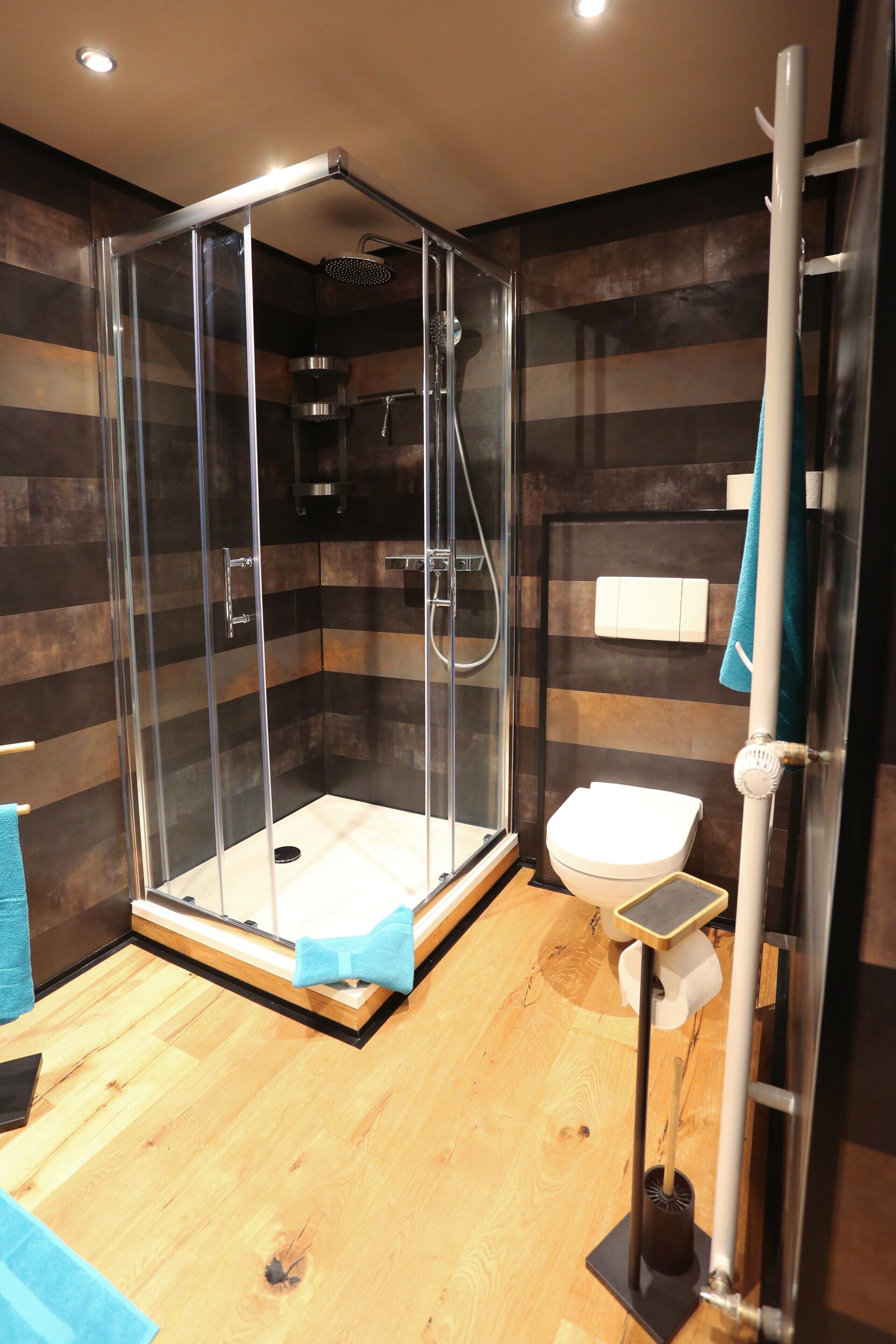Une salle de bain moderne avec une douche à parois de verre, des toilettes et un porte-serviettes.