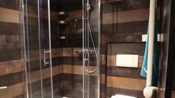 Une salle de bain moderne avec une douche à parois de verre, des toilettes et un porte-serviettes.