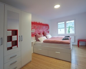 A bedroom with a bed, wardrobe, and a window. - Apartment 'Quartierblancdenoir Blanc' with Private Terrace and Wi-Fi (Reil)