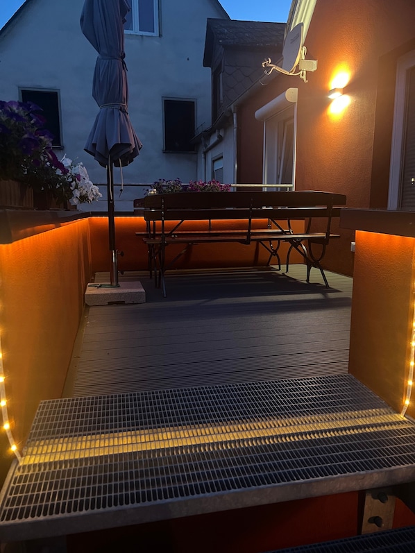 An outdoor patio with a metal grill table, a bench, and a potted plant. - Apartment 'Quartierblancdenoir Blanc' with Private Terrace and Wi-Fi (Reil)