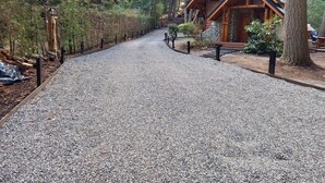 A gravel path leading to a wooden cabin in a forested area. - Cabañas El Remanso (Puerto Manzano)