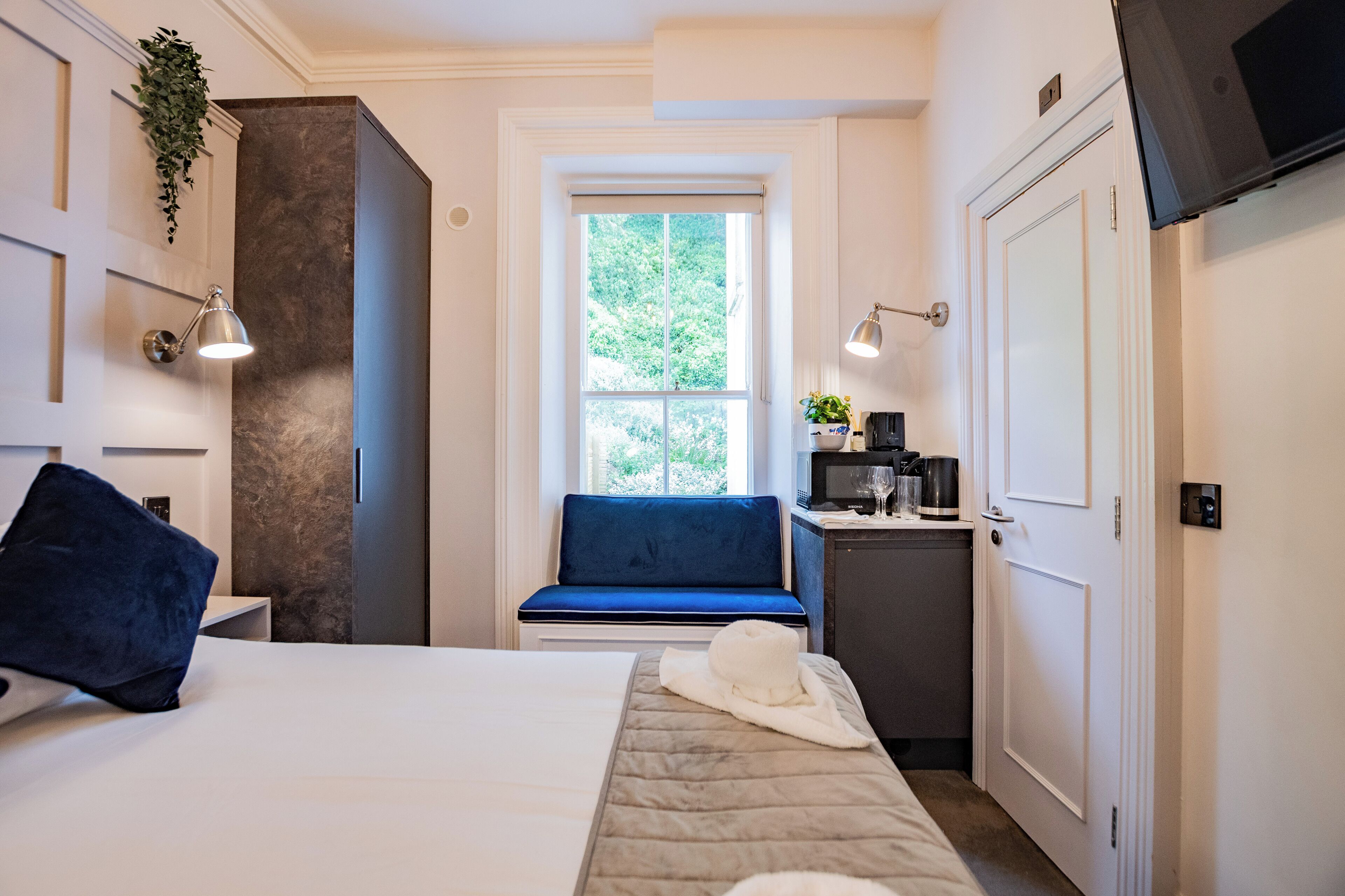 A hotel room with a bed, a small seating area, a microwave, and a television.