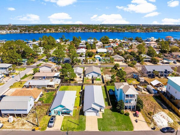 An aerial view of a residential area with houses, a clear blue sky, and a body of water in the background. - 3-bedroom, 2-bathroom retreat just 5-minute walk from the pristine beach! (Panama City Beach)