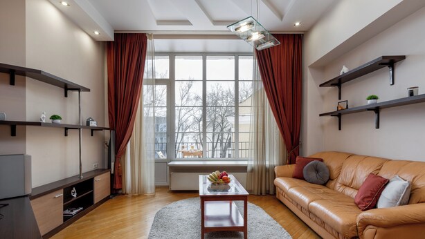A modern living room with a leather sofa, a glass coffee table, and built-in shelves. - 3-room apart near the shopping center (Minsk)
