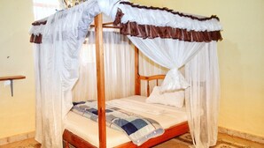 A four-poster bed with a canopy, a wooden frame, and a mattress with a blue and white blanket. - Adonai Resort Voi (Voi)