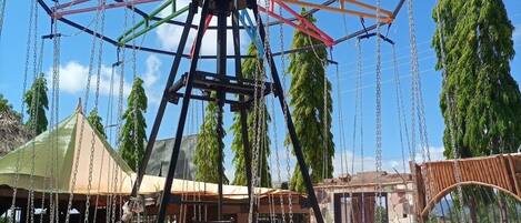 A Ferris wheel with multiple cabins, surrounded by a park area with benches and trees.
