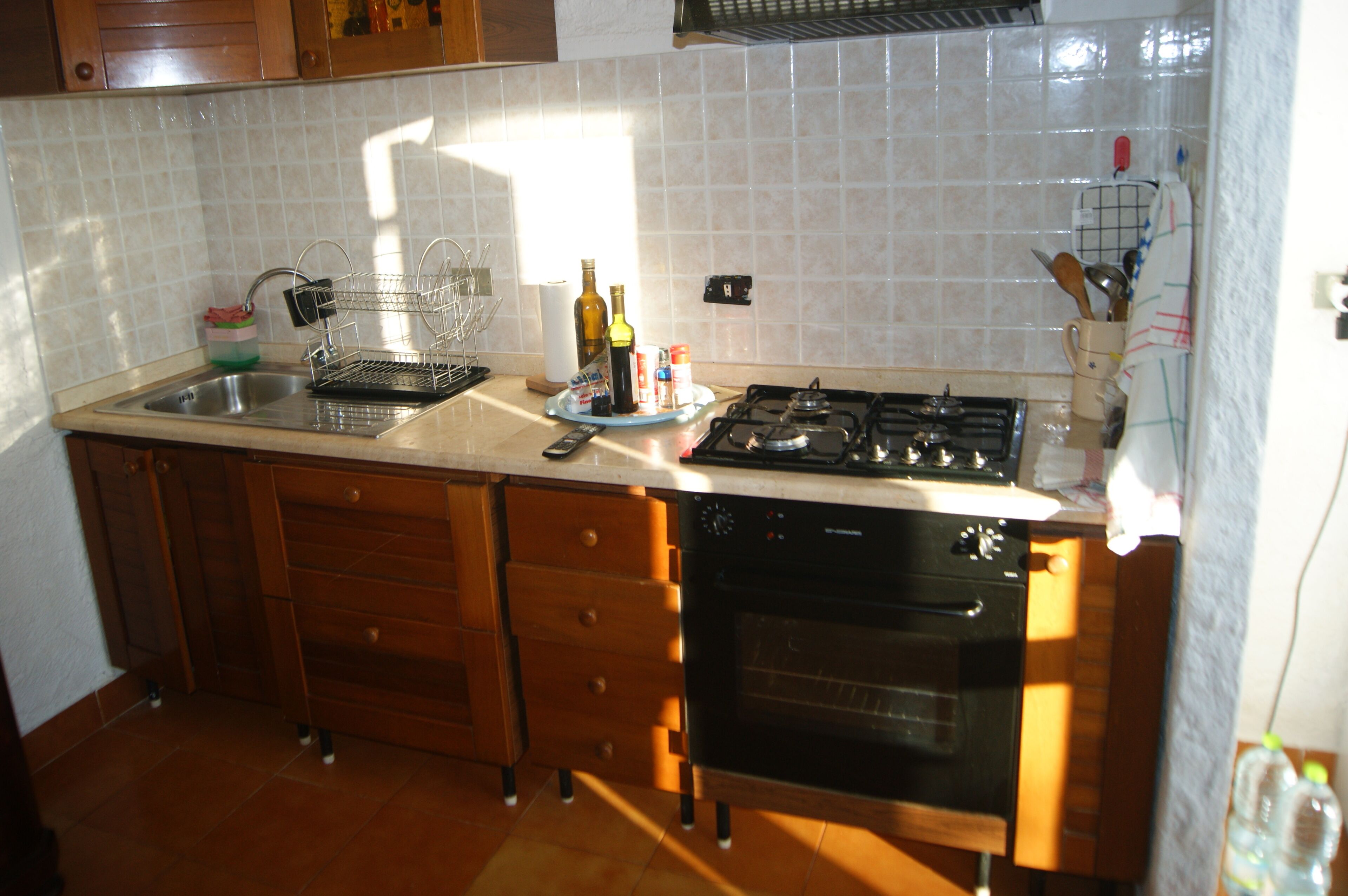 Una cocina con un lavamanos, estufa, horno y armarios de madera.