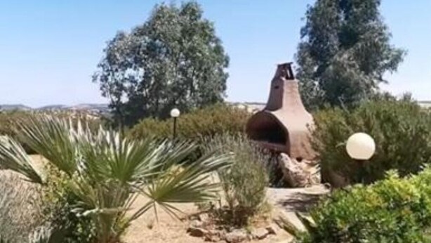 Een woestijntuin met een grote structuur van terracotta potten, omringd door verschillende woestijnplanten en bomen.