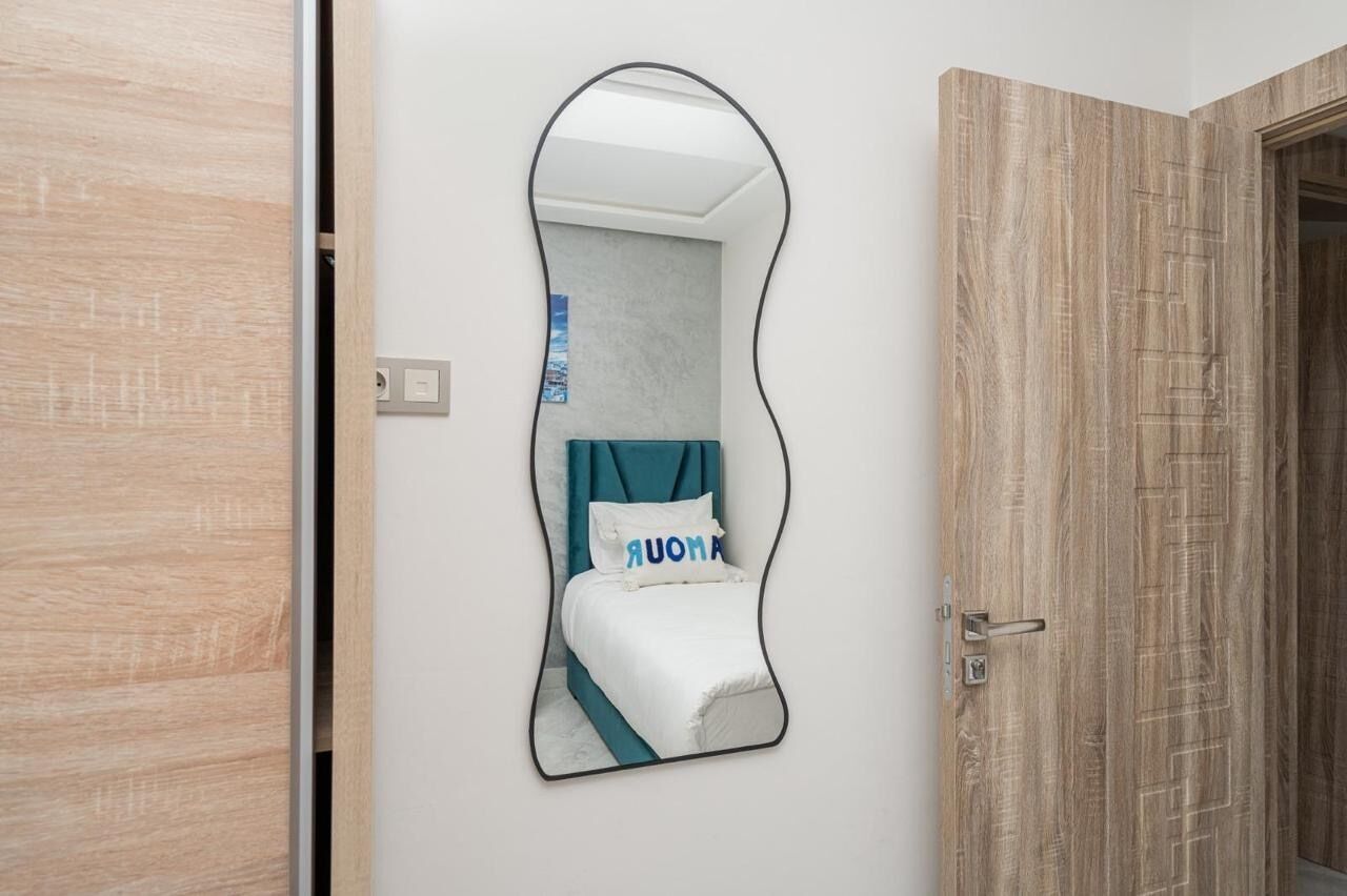 Ein Schlafzimmer mit einem Bett, einem Spiegel und einer Holztür.