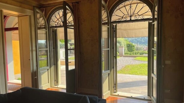 Una habitación con grandes ventanales y vistas a un jardín ajardinado.